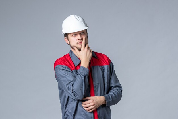 front view male builder in uniform and helmet on gray background