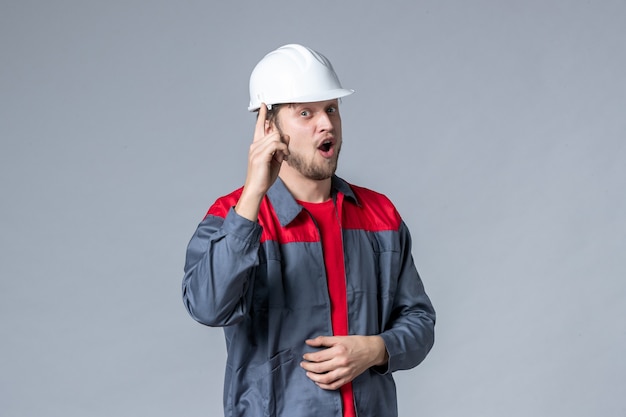 front view male builder in uniform and helmet on gray background