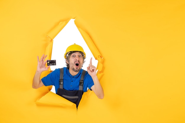 Free Photo front view male builder in uniform holding black bank card on yellow background