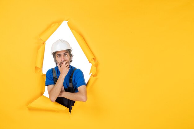 Front view male builder in uniform on the yellow background