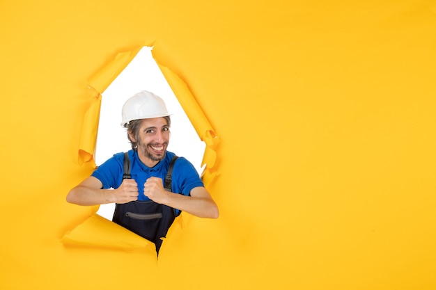 Front view male builder in uniform on yellow background