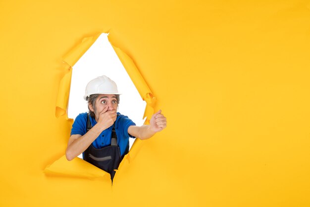 Front view male builder in uniform on yellow background