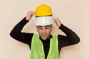 Free photo front view male builder wearing two helmets on light background