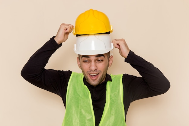 Free Photo front view male builder wearing two helmets on light background