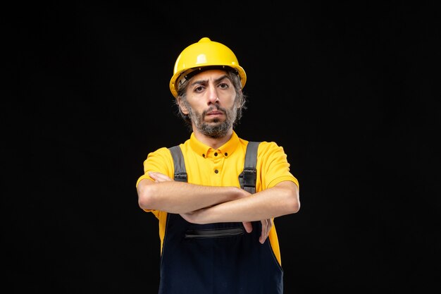 Front view of male builder in yellow uniform on black wall