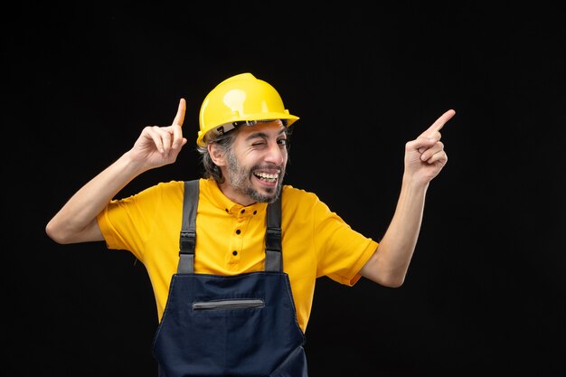 Front view of male builder in yellow uniform on black wall