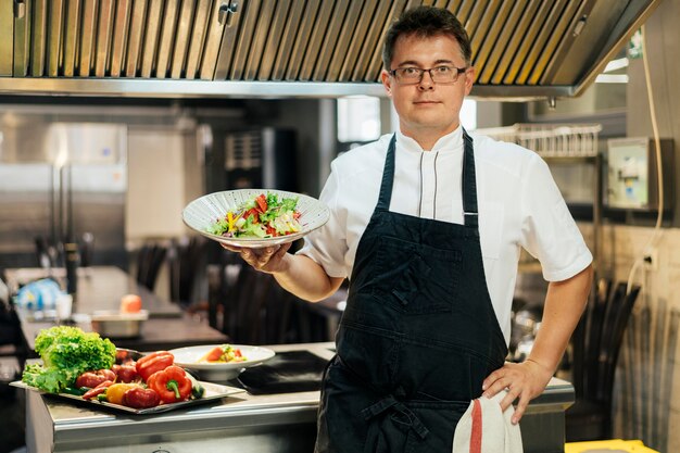 Front view of male chef holding dish