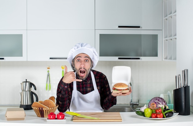 Free Photo front view of male chef making call me sign holding up burger in the kitchen