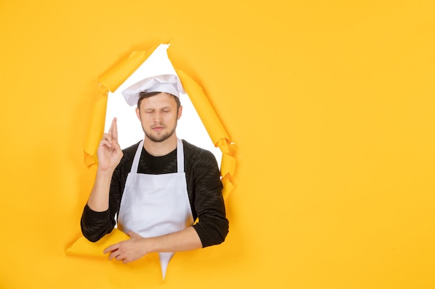 Front view male cook in white cape and cap on the yellow ripped job color white photo kitchen food man cuisine