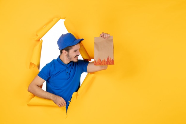 Free Photo front view male courier in blue uniform holding food package on a yellow space