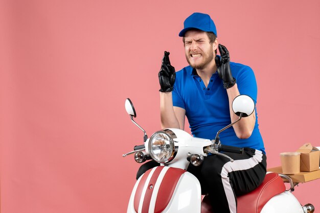 Front view male courier in blue uniform on pink 