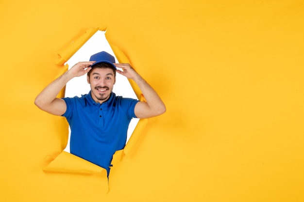 Free photo front view male courier in blue uniform smiling on yellow space