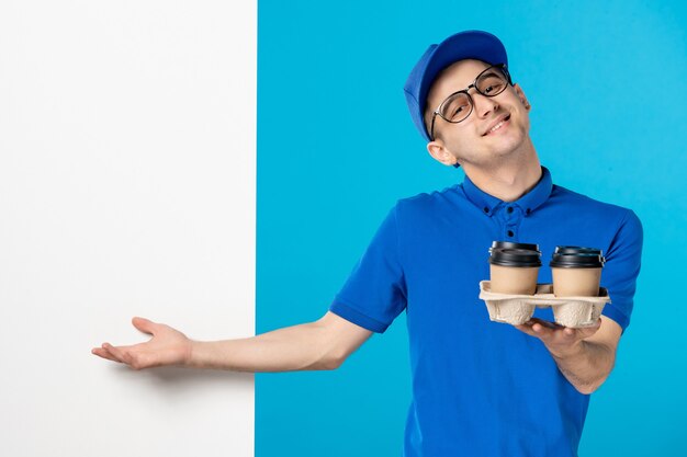 Front view of male courier in blue uniform with coffee on blue 