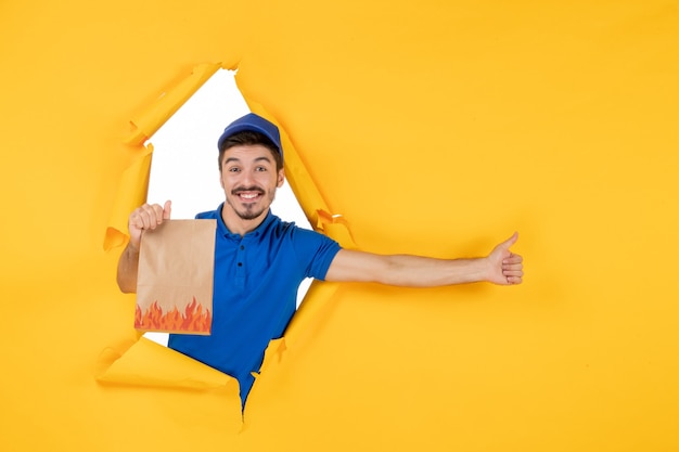 Free Photo front view male courier in blue uniform with food package on the yellow space