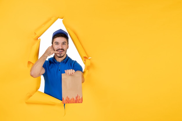 Free Photo front view male courier in blue uniform with food package on yellow space