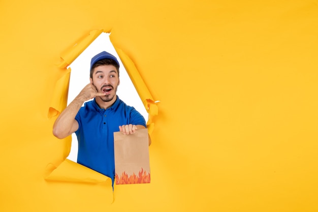 Free Photo front view male courier in blue uniform with food package on yellow space