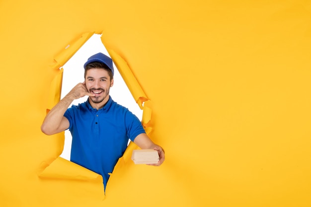 Free Photo front view male courier holding little food package on a yellow space