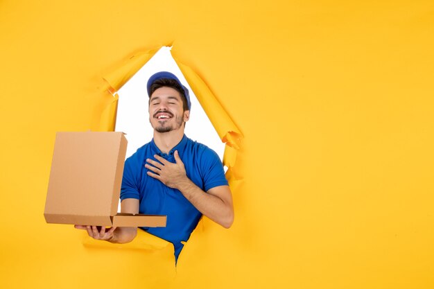 Front view male courier holding opened pizza box on yellow space