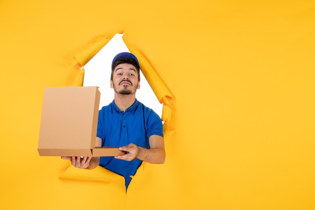 Front view male courier holding opened pizza box on yellow space