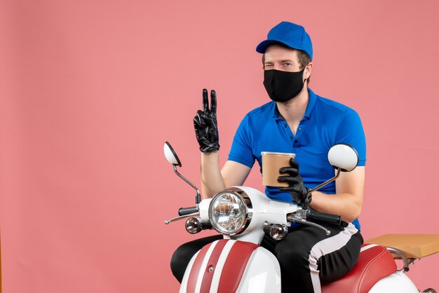 Front view male courier sitting on bike and holding coffee on the pink 