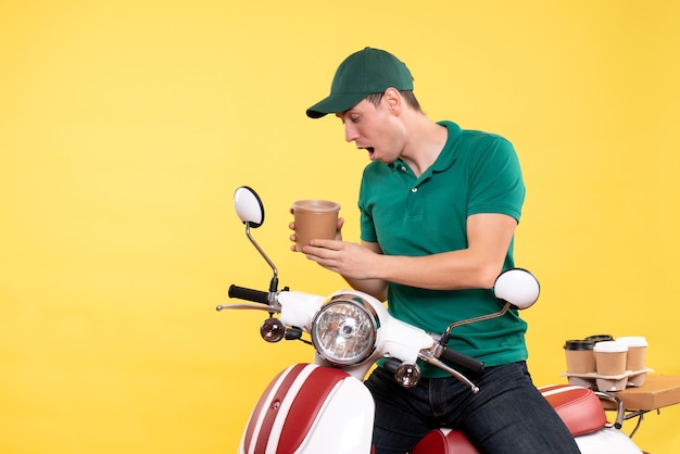 Free Photo front view male courier in uniform holding coffee cup on yellow 