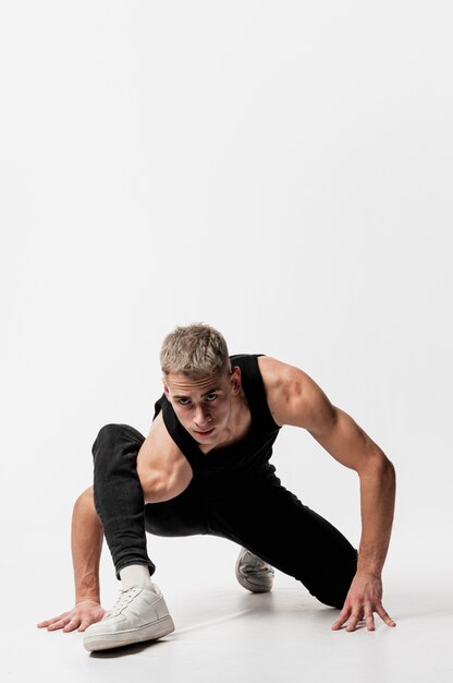 Front view of male dancer in jeans and tank top posing with copy space