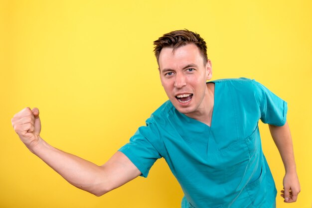 Front view of male doctor emotionally posing on yellow wall