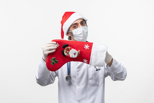 Front view male doctor holding big holiday sock on white desk virus covid- holiday