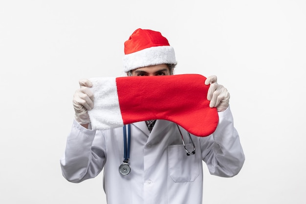 Front view male doctor holding big holiday sock on white wall virus covid holiday