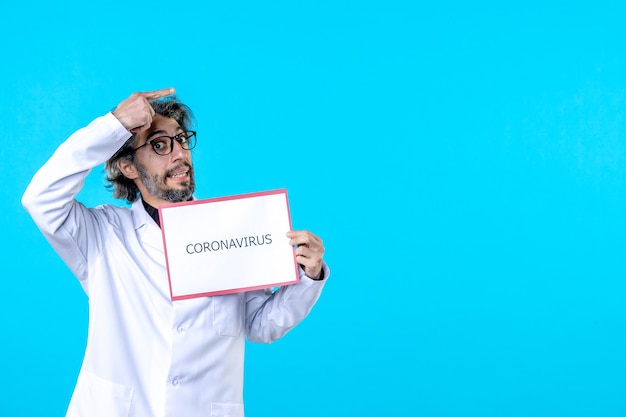 Free photo front view male doctor holding coronavirus writing on blue