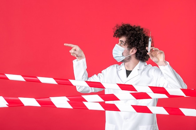 Free Photo front view male doctor holding injection against virus on red background warning covid- health medical quarantine uniform