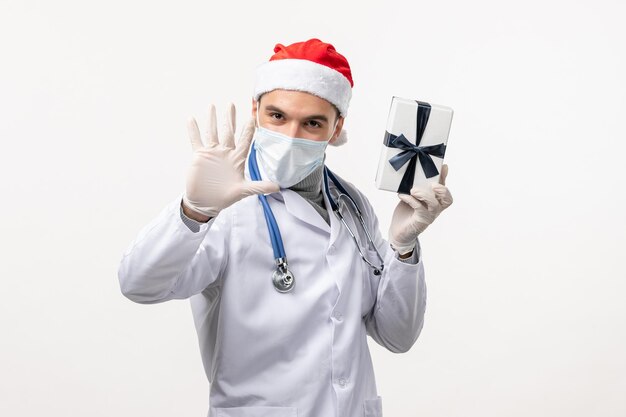 Front view of male doctor holding present on white wall