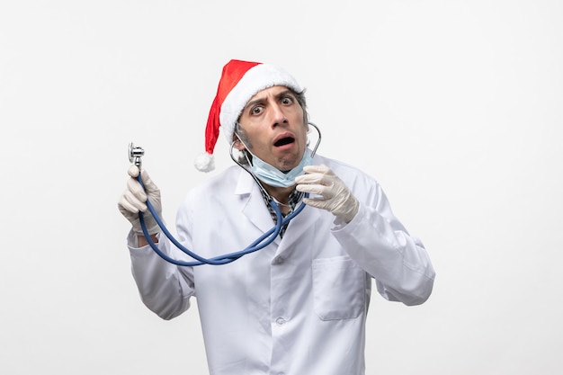 Free photo front view male doctor holding stethoscope on white floor virus covid- emotion