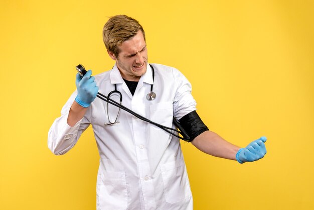 Front view male doctor measuring his pressure on yellow desk virus health medic