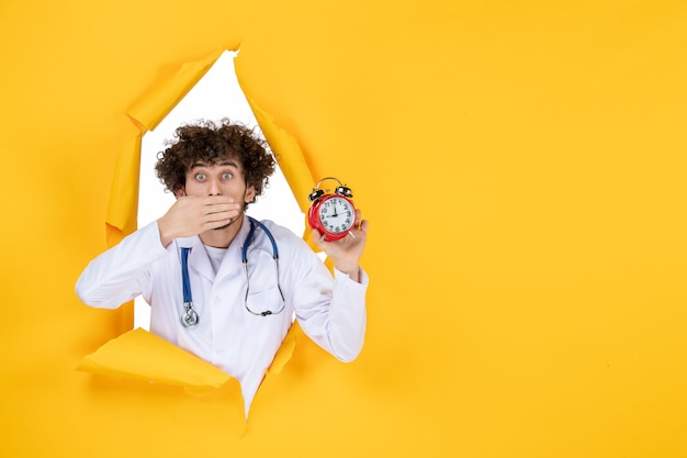 Free photo front view male doctor in medical suit holding clocks on yellow health hospital medic shopping medicine time