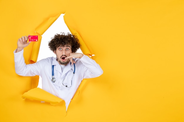 Free Photo front view male doctor in medical suit holding red bank card on yellow colors medicine hospital disease health virus medic money