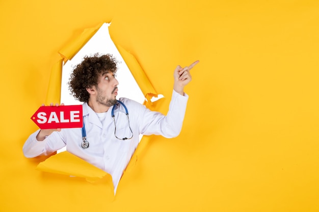 Free Photo front view male doctor in medical suit holding red sale writing on yellow medic color health disease shopping hospital