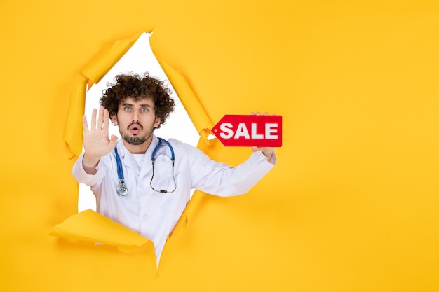 Free Photo front view male doctor in medical suit holding red sale writing on a yellow medic color health disease virus shopping hospital