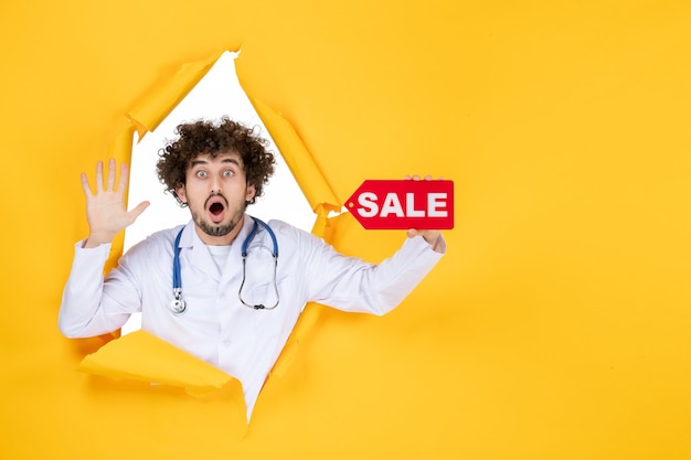 Free Photo front view male doctor in medical suit holding red sale writing on yellow medic color health disease virus shopping hospital