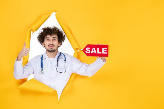 Free Photo front view male doctor in medical suit holding red sale writing on a yellow medic color health hospital disease virus shopping