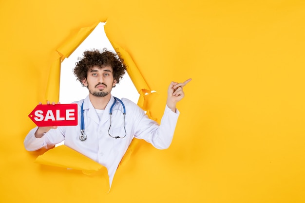 Free Photo front view male doctor in medical suit holding red sale writing on yellow medic color health virus shopping hospital