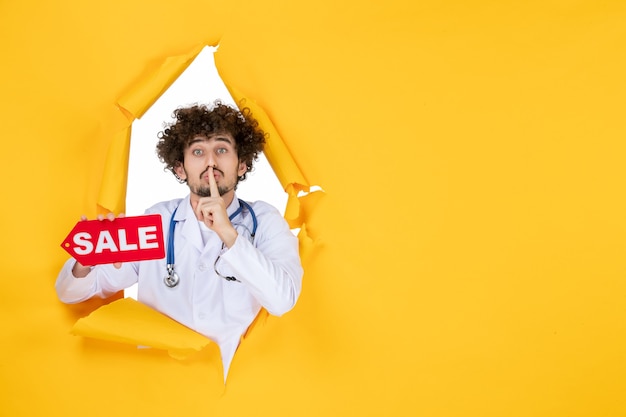 Free Photo front view male doctor in medical suit holding sale writing on yellow shopping color health hospital medicine