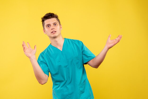 Front view of male doctor in medical suit on yellow wall