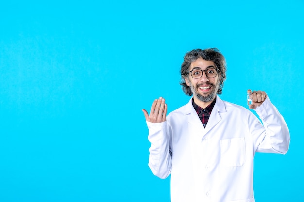 Free photo front view male doctor in medical uniform holding little flask on blue