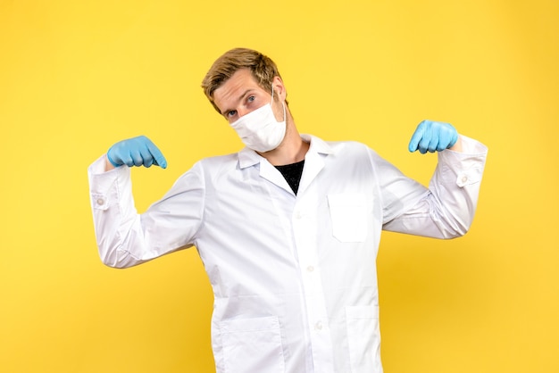 Front view male doctor pointing on yellow background pandemic covid health medic