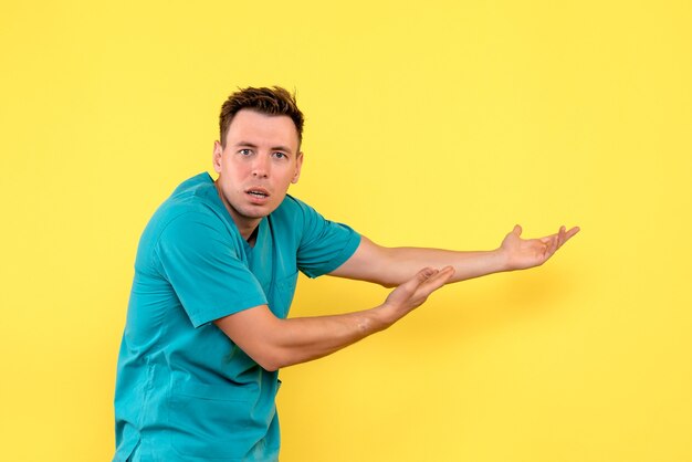 Front view of male doctor posing on yellow wall