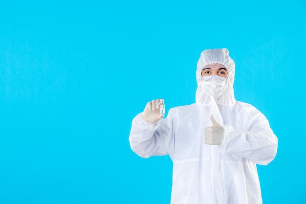 Front view male doctor in protective suit and mask on blue