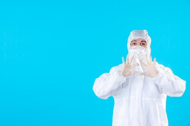 Front view male doctor in protective suit and mask on blue