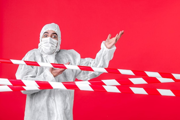 Front view male doctor in protective suit and mask on red background health cure hospital covid- quarantine color isolation