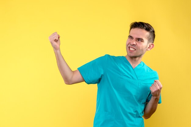 Front view of male doctor rejoicing on yellow wall